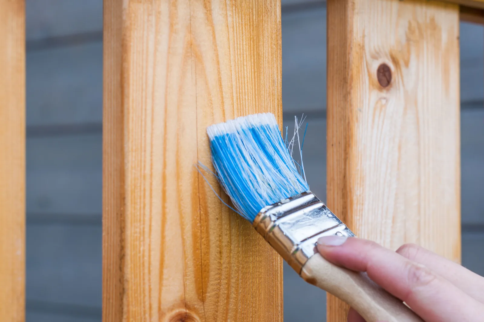 Applying wood stain with a brush, representative of deck and fence staining work